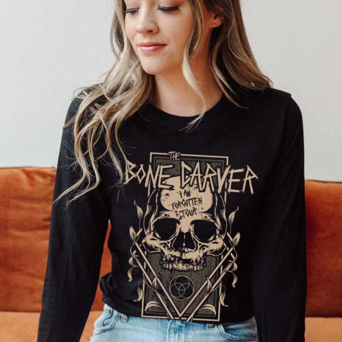 Bone Carver Long Sleeve T-Shirt on a model seated on an orange sofa. ACOTAR merch.