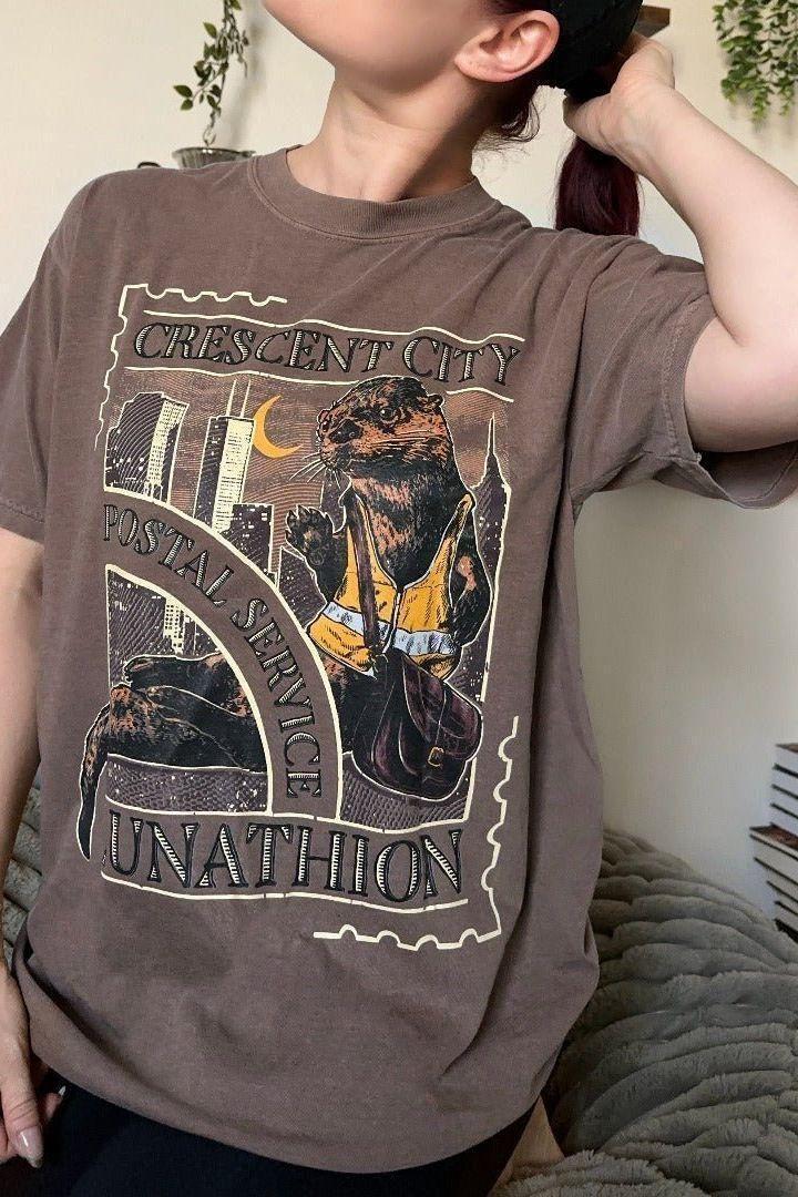 CC Otters T-Shirt — Crescent City merch by Sarah J. Maas. Bryce's museum job — the era before everything changed. Hand-designed in Australia, officially licensed.