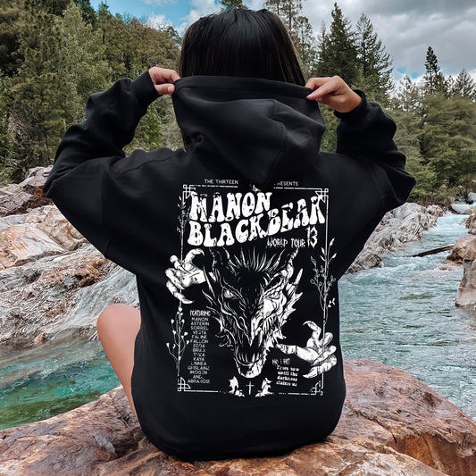 Back view of a model pulling up the hood of a black Manon Blackbeak hoodie printed with a white wyvern gig poster, inspired by Throne of Glass by Sarah J. Maas