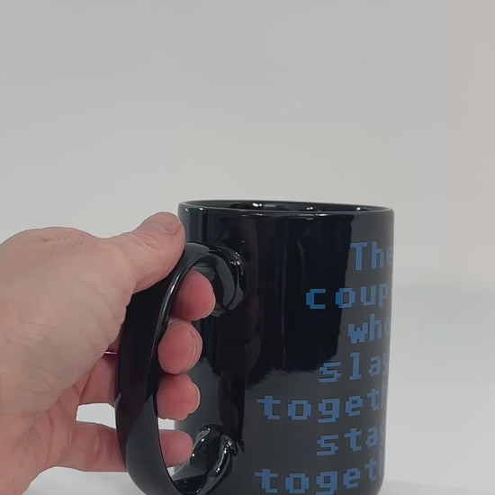 Product video: the black Slay Together Stay Together mug turned by hand — the blue stacked lettering reading 'the couple who slays together stays together' [focal 50 70]