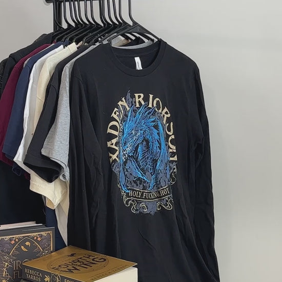Product video: the black Xaden Riorson t-shirt — the blue dragon in an arched frame with XADEN RIORSON curved around it and 'holy fucking hot' beneath [focal 50 40]
