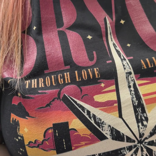 Try-on video: the black Bryce Quinlan t-shirt — BRYCE in red above the compass star over the Lunathion skyline, 'through love all is possible' across it and 'Starborn Tour' beneath [focal 50 30]
