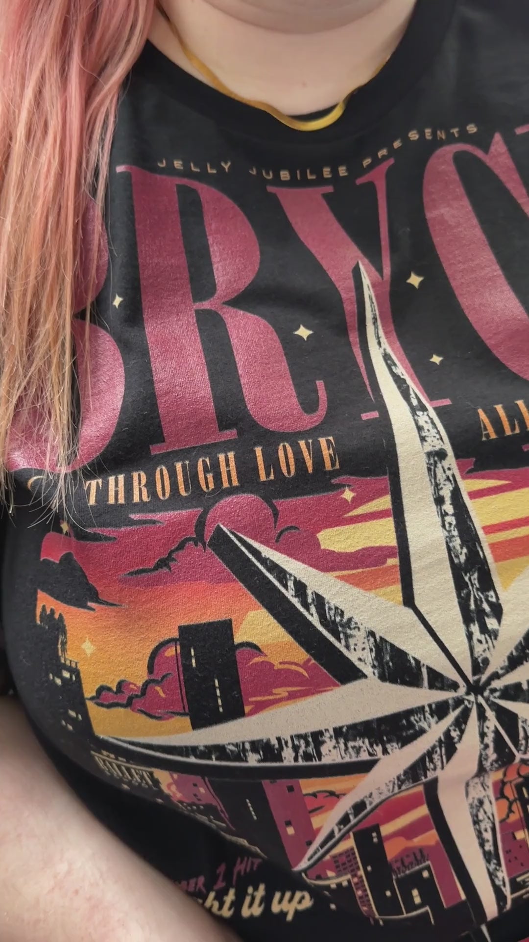 Try-on video: the black Bryce Quinlan t-shirt — BRYCE in red above the compass star over the Lunathion skyline, 'through love all is possible' across it and 'Starborn Tour' beneath [focal 50 30]
