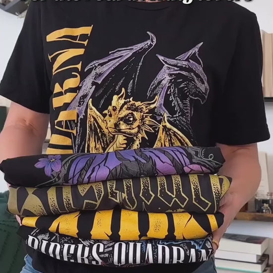 Try-on video: the black Violence t-shirt — the stained-glass arch in purple and lilac with the dark winged dragon, the golden hatchling at its base, 'Violence' above and 'I will not die today' along the plinth [focal 50 35]