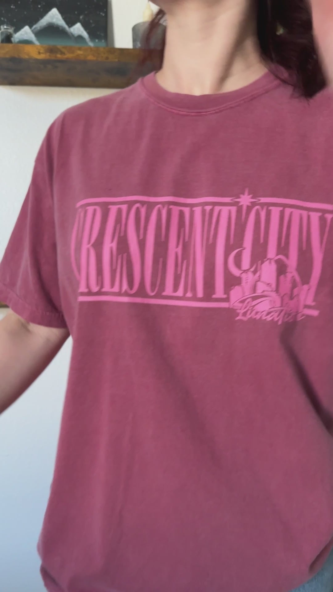 Try-on video: the maroon Crescent City Location t-shirt — the pink outline CRESCENT CITY lettering with the small Lunathion mark beneath [focal 50 40]