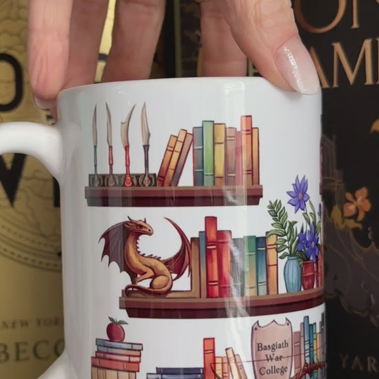 Product video: the Fourth Wing Shelfie mug turned by hand — the painted bookshelf wraps right round, shelves of books with the dragon figurine, the plant and the framed quote panel [focal 50 60]