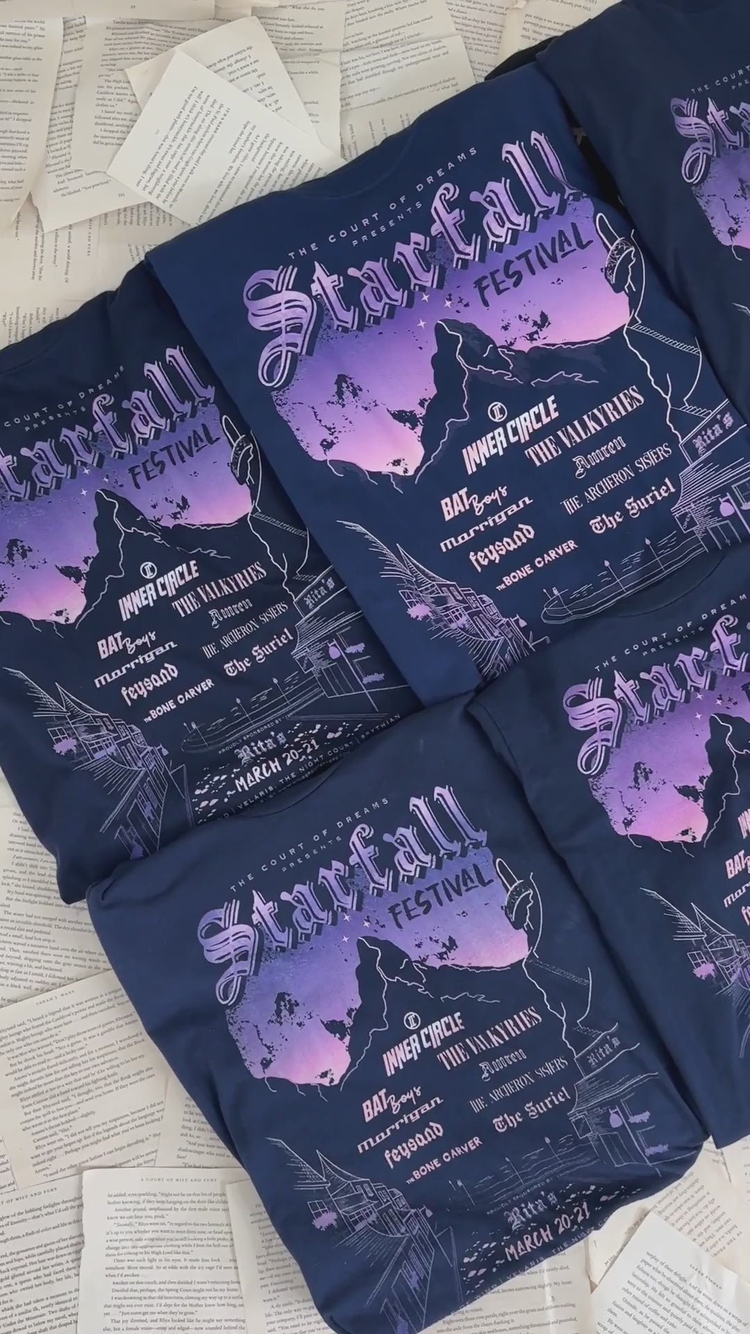 Product video: the navy Starfall Festival t-shirts folded — the lilac and peach mountain poster with the Inner Circle line-up beneath the Starfall Festival lettering [focal 50 40]