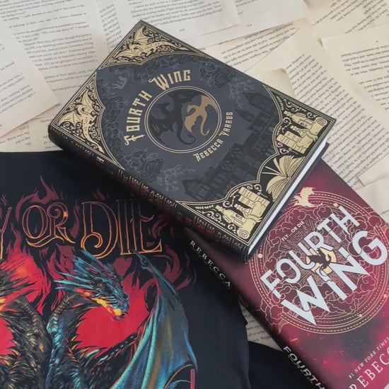 Flat lay video: the black Fly or Die t-shirt with the Fourth Wing and Iron Flame hardbacks — the red and blue dragons facing off beneath the FLY OR DIE lettering [focal 50 55]