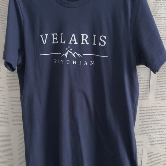Product video: the navy Velaris t-shirt on a hanger — the white VELARIS wordmark above the starred mountain line and PRYTHIAN beneath [focal 50 20]