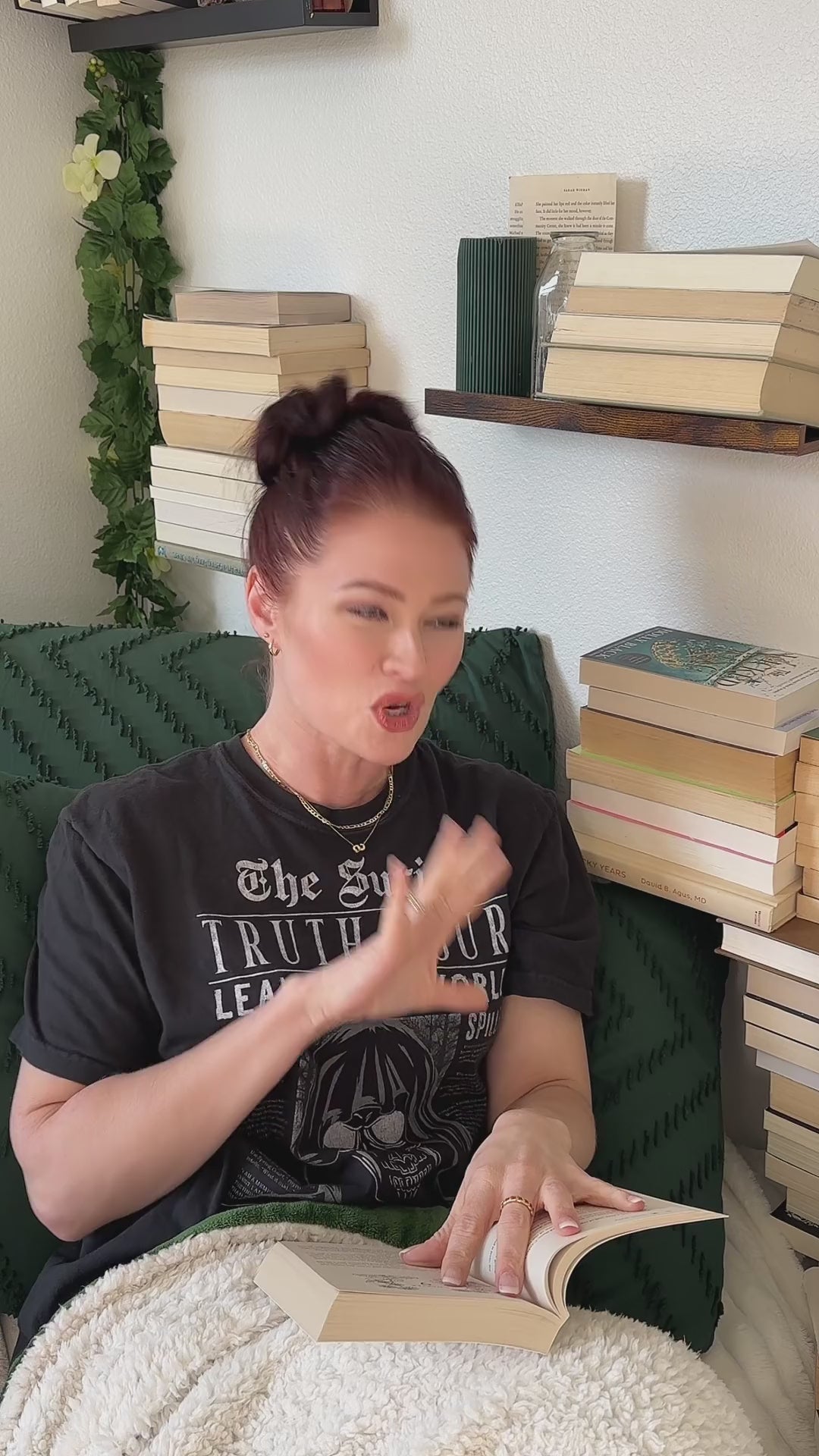 Lifestyle video: the black Suriel t-shirt worn while reading — 'The Suriel / TRUTH TOUR / LEAVE THIS WORLD' above the hooded skull, 'a better place than you found it' along the hem [focal 50 55]