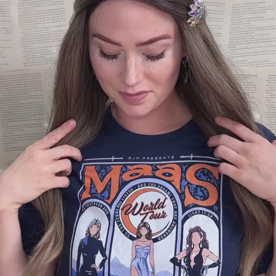 Try-on video: the navy Maasverse t-shirt — the art-nouveau tour poster with MAAS in peachy orange, the World Tour roundel, the three figures in their arches and 'you do not yield' beneath [focal 50 70]