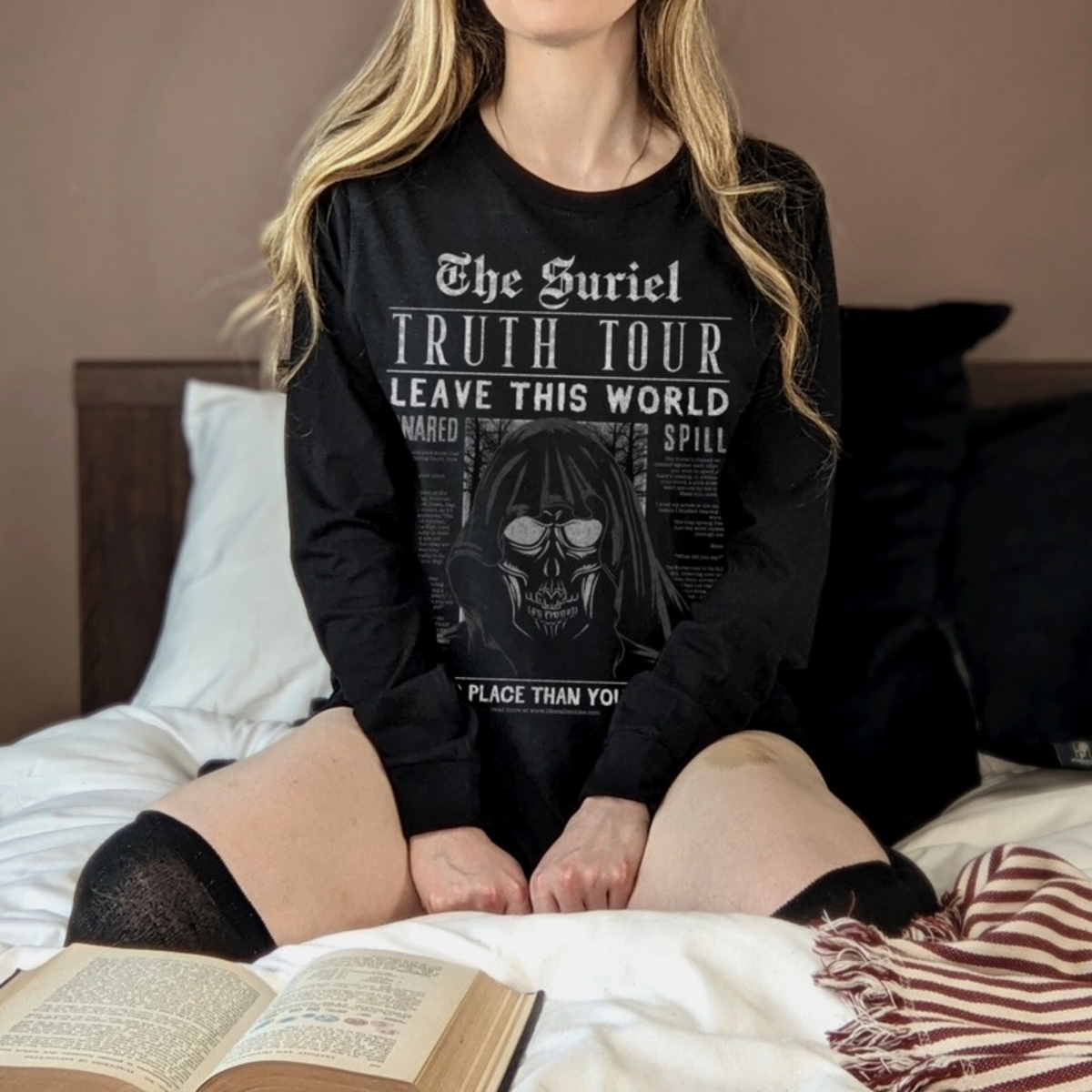 The Suriel Long Sleeve T-Shirt worn on a bed with an open book. ACOTAR merch.